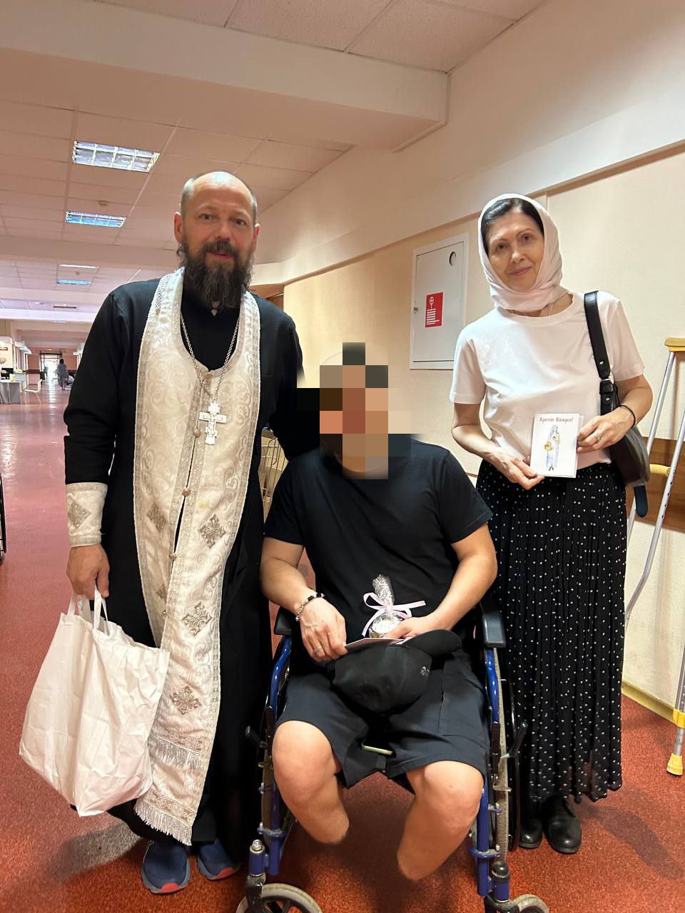 Священник и сестра милосердия навещают пациента